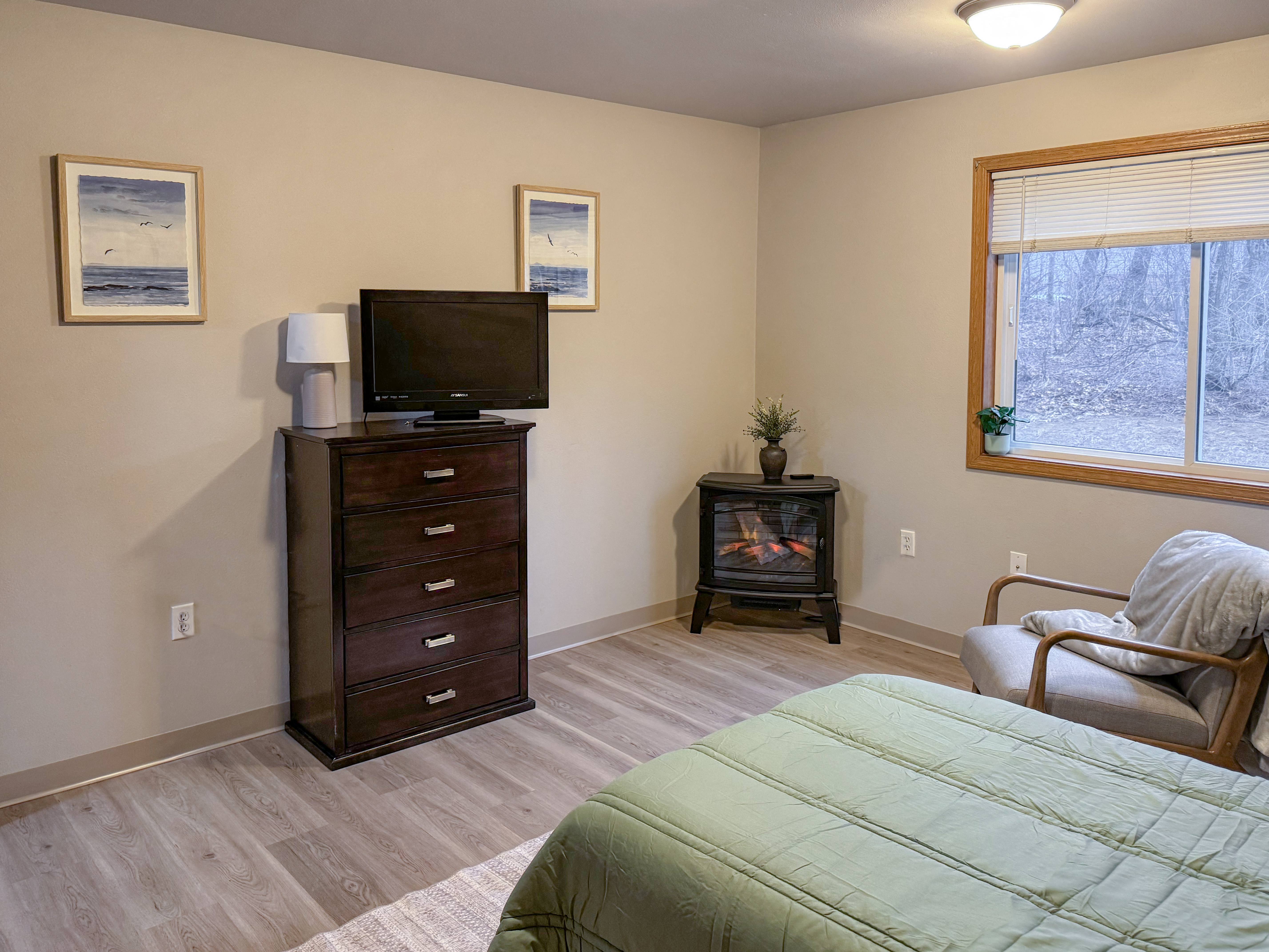 A bedroom with a bed, dresser, chair, and window.
